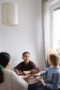 Girl and boys playing scrabble at dining table