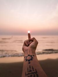 Human hand on beach during sunset