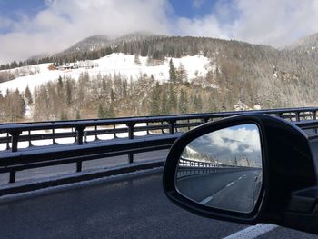 Reflection of trees on snowcapped mountain against sky