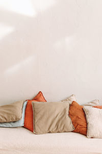 Colored pillows from natural eco materials on the beige bed in a light interior design. copy space