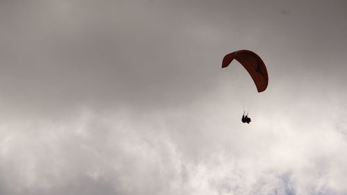 Low angle view of person paragliding against sky