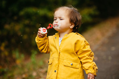 Cute boy holding yellow while standing outdoors