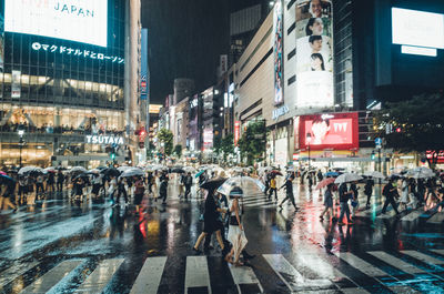 Crowd on wet city street at night during rainfall