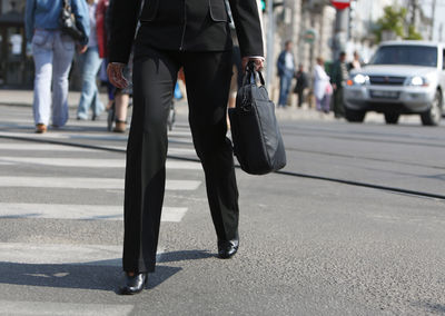 Low section of woman wearing suit walking on city street