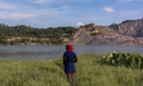 Rear view of boy looking at lake against sky