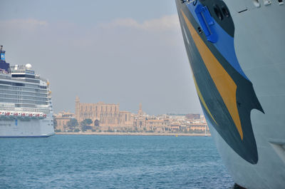 Ship sailing on sea against buildings in city