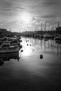 Boats moored at harbor against sky