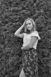 Portrait of smiling young woman standing against plants