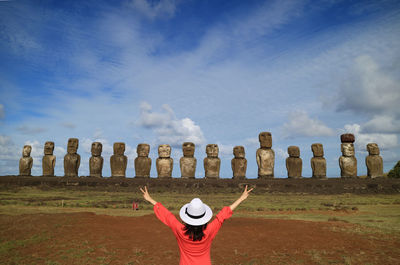 Rear view of person with arms raised against sky