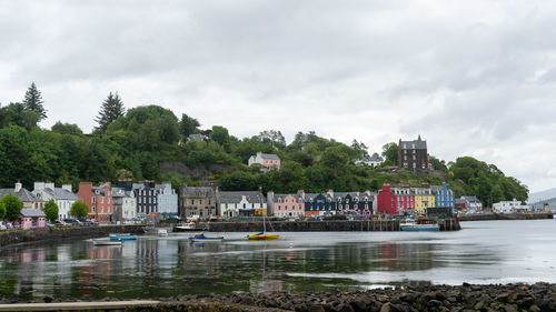 Buildings by river against sky