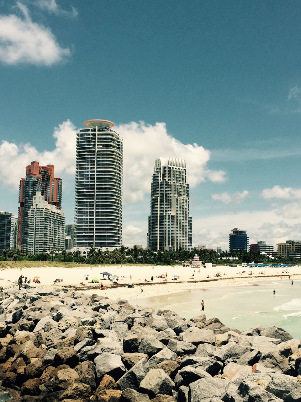 building exterior, architecture, built structure, beach, sky, city, sand, cloud - sky, shore, day, cloud, blue, incidental people, modern, sea, building, sunlight, outdoors, skyscraper, travel destinations