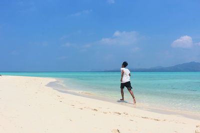 Rear view of man running on beach against sky