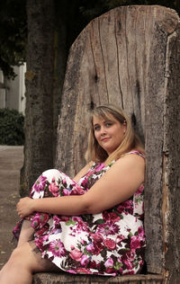 Beautiful woman holding pink flowers in front of tree