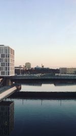 Reflection of city in water against clear sky