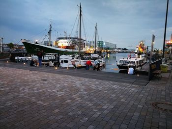 Sailboats moored at harbor against sky in city