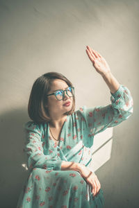 Woman shielding eyes against wall