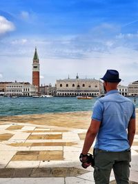 Rear view of man standing by buildings against sky