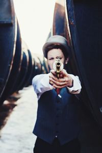 Well-dressed man pointing gun by steam train