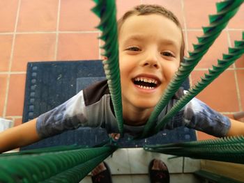 Portrait of laughing cute boy playing with ropes while standing on doormat