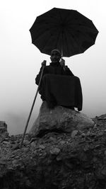 Woman holding umbrella on rock