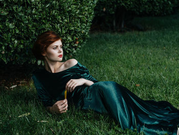 Young woman sitting on grass in land