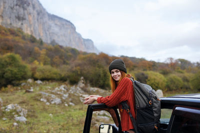 Portrait of smiling young woman standing by car