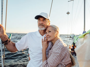 Smiling senior couple standing on boat during sunset