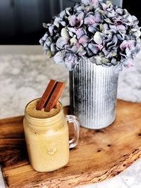 Close-up of purple hydrangeas in vase by chocolate smoothie on table