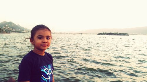 Portrait of smiling boy standing at beach against clear sky