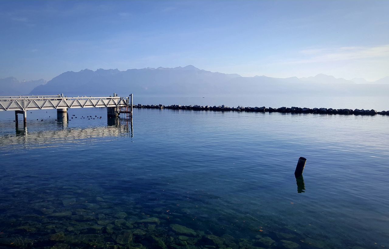 water, mountain, beauty in nature, scenics, nature, lake, tranquility, outdoors, tranquil scene, sky, no people, day, mountain range, blue, built structure, architecture, bird