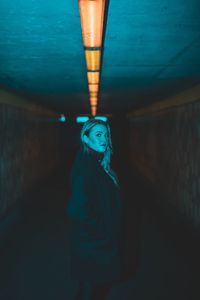 Portrait of woman standing against illuminated wall