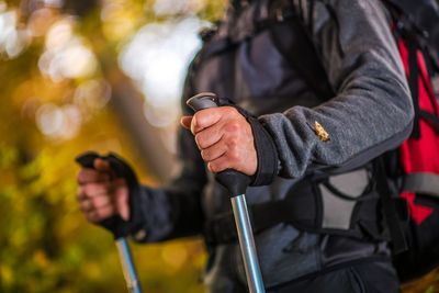 Midsection of hiker holding poles