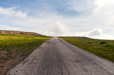 Road amidst field against sky