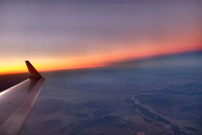 Airplane flying over sea against sky during sunset