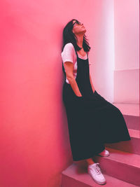 Midsection of woman standing against purple wall