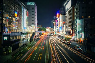 Light trails on road amidst buildings at night