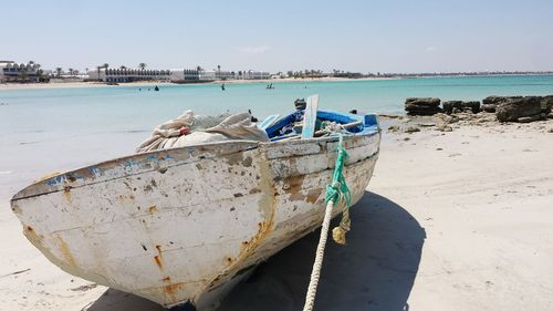 Boat moored on beach against sky