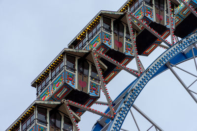 Low angle view of ferris wheel by building against clear sky