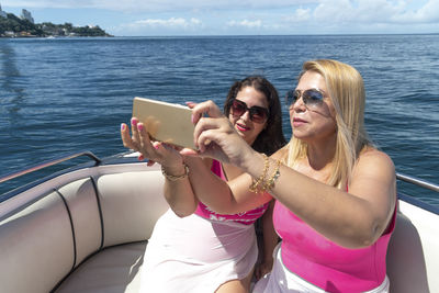 Female friends on top of a boat against the sea in the background. 