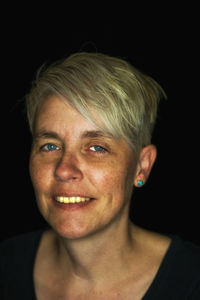 Close-up portrait of a smiling young woman pixie haircut blond