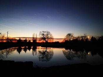 Silhouette trees by lake against sky during sunset