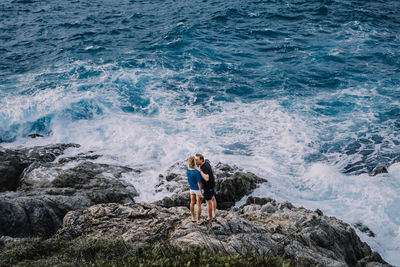 Full length of man standing on rocks at sea