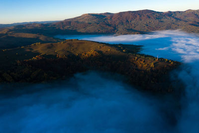 Aerial drone view of mist and clouds in the valley in sunrise. flying above the clouds