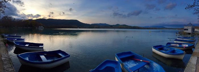 Boats moored at harbor against sky during sunset