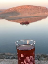 Close-up of drink in lake against mountain range