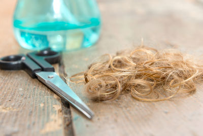 High angle view of hair and scissors by bottle on table