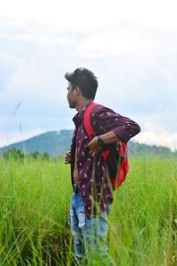 Young man with backpack standing on land