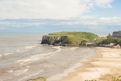 Scenic view of beach against cloudy sky