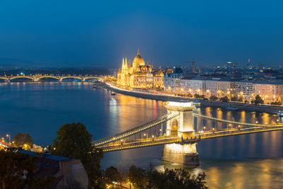 Illuminated bridge over river against sky at night