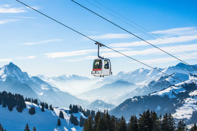 Overhead cable car over snowcapped mountains against sky